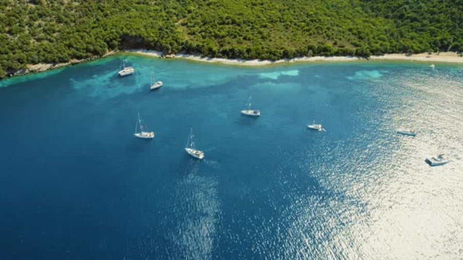 Aerial View Of Anchored Sailboats Near A Lush Coastal Beach During aerial-view-of-anchored-sailboats-near-a-lush-coastal-beach-during