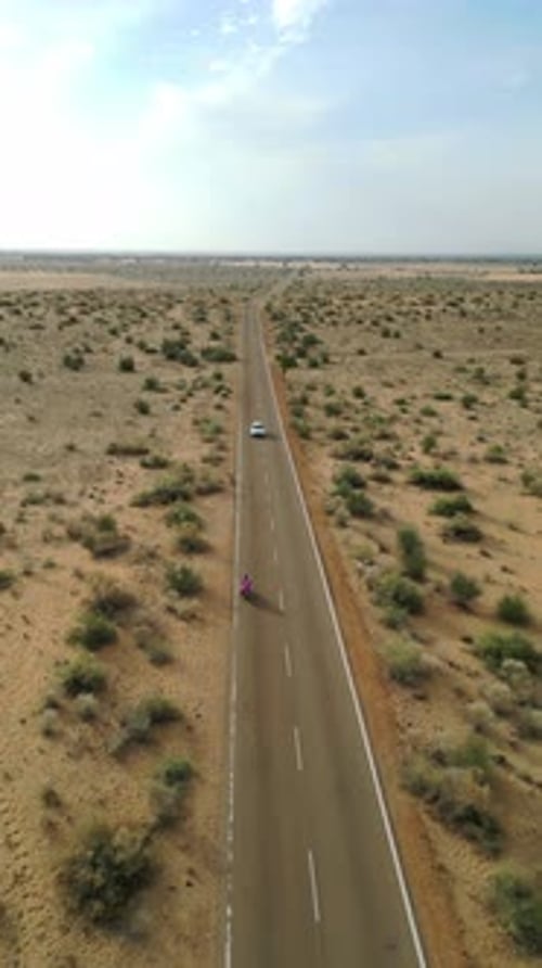 Vue aérienne de la conduite d'une voiture et d'un vélo sur la route de Longewala par une journée ensoleillée au Rajasthan