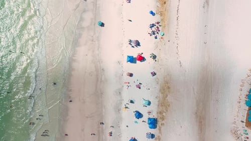 Top-down aerial view of shoreline with umbrellas and turquoise waves