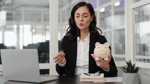 Businesswoman Saving Money in Piggy Bank at Office