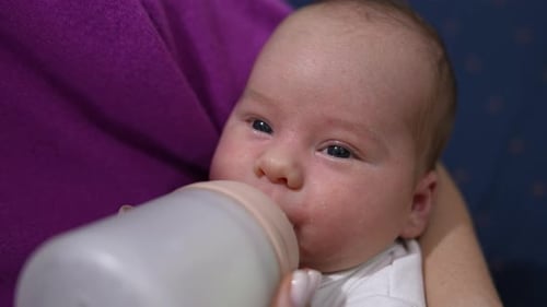 Infant Drinking Milk From Bottle Close Up