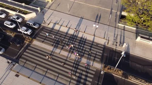 Aerial top down shot of pedestrian walking by crosswalk in Buenos Aires City at sunset - tilt down
