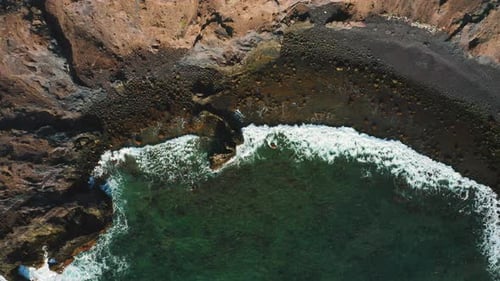Wilder, vulkanischer, ruhiger Meeresstrand, Wellen krachen an der felsigen Küste von Sand und Steinen