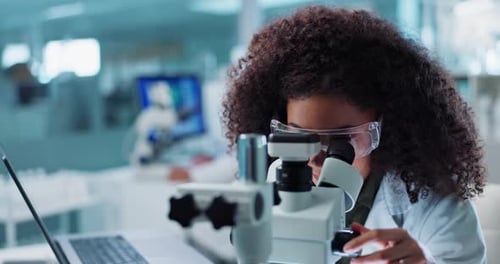 Woman with Microscope in Brightly Lit Laboratory