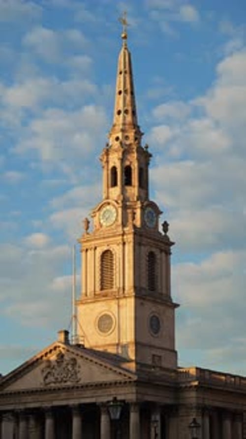 Tall clock tower of the St Martin-in-the-Fields church captured under a partly cloudy sky in London,