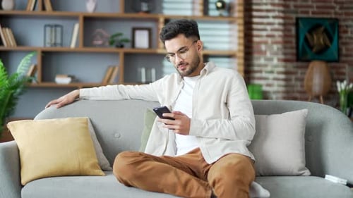 Adult Using Smartphone Relaxing on Sofa
