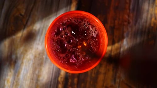 Top View of Cola Pouring Into an Orange Glass Filled with Ice
