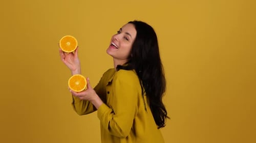 Happy Young Woman with Orange Halves on Yellow