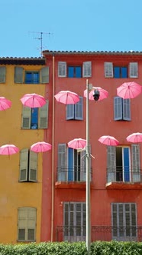 Rows of pink umbrellas above the streets of the old town in Grasse, France. Vertical