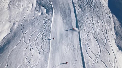 three skiers ride down a beautiful slope and blowing up snow when driving curves on the track.