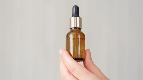 Hand Holding Bottle with Dropper