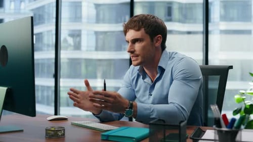 Energetic businessman talking with colleagues in online video conference at office