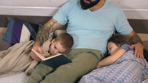 Father Reading Bedtime Story to Children in Bed