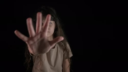Young Girl Makes Stop Gesture Against Black Background
