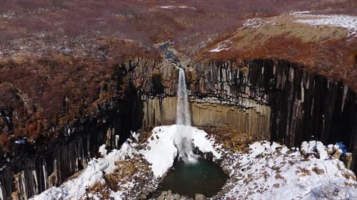 Small Waterfall cascades into frozen lake, geological formation after eruption