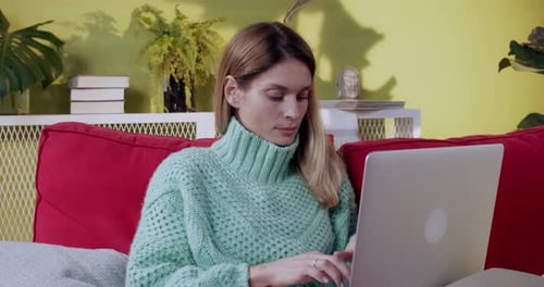 Woman Typing on Laptop while Relaxing on Couch