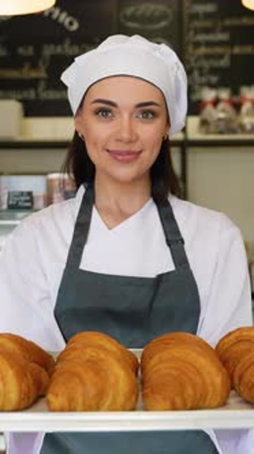 Smiling Woman Holding Tray of Fresh Croissants