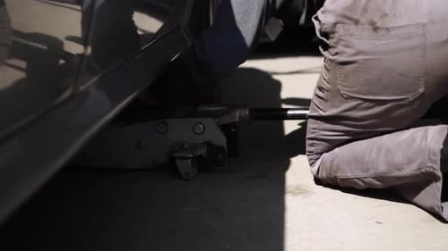 Man Lifting Car with a Jack in Garage
