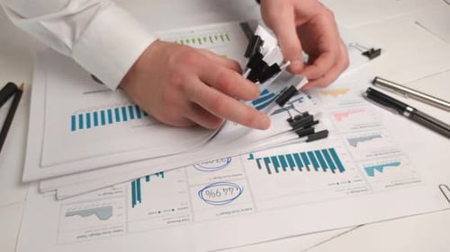 Hands Attaching Binder Clips to Charts