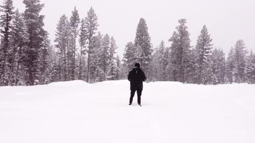 Luftaufnahme eines Mannes, der im Schnee läuft und dabei eine Fernbedienung hält.