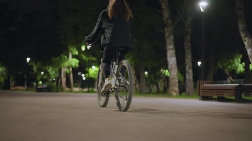 Quiet Cycling Through Illuminated Park Calm Journey Beneath Glowing Streetlights At Night Tranquil