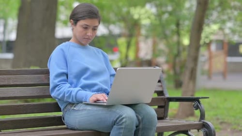 Young Woman Using Laptop Computer in Park