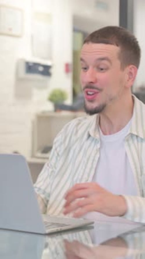 Excited Young Man Receives Good News on Laptop