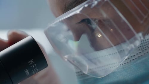 Female Scientist Looking Through Microscope in Laboratory