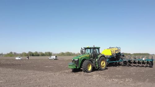 Blauer Traktor arbeitet auf dem Feld und pflanzt Sonnenblumen in der Ukraine