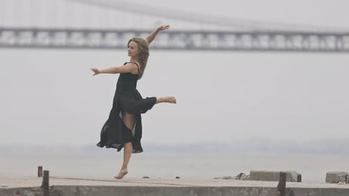 An Adult Woman in Black Dress Dancing on the Pier