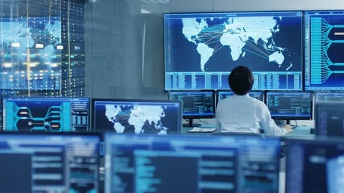 In the System Control Room Operator Sits at His Workstation with Multiple Displays Showing Graphics