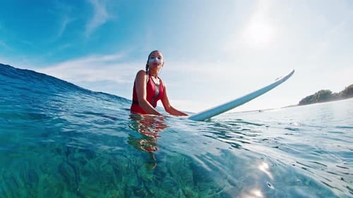 Woman Surfer Sitting on Surfboard in Tropical Ocean
