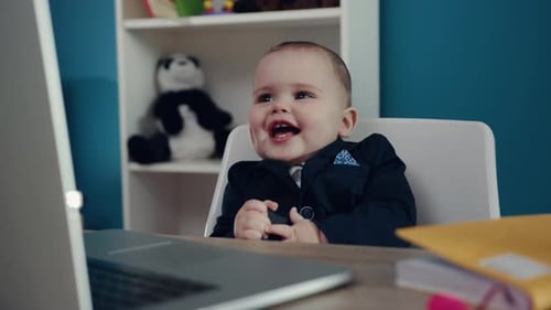 Baby Sits at Desk Wearing Suit Looking at Laptop