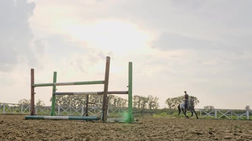 Eine Jockeyfrau springt in einem Springwettbewerb in Zeitlupe über die Barrieren auf einem Pferd