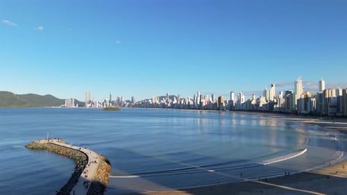 Zumbido panorámico vuela al Balneário Camboriú, junto a la playa curva del Océano Atlántico con el horizonte de la ciudad,