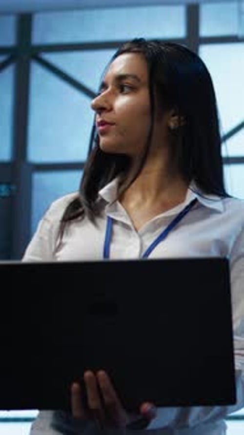 Vertical Video Tracking Shot of Woman in Server Hub Ensuring Networks are Secure