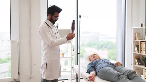 Doctor Monitoring Woman Receiving IV Drip in Hospital