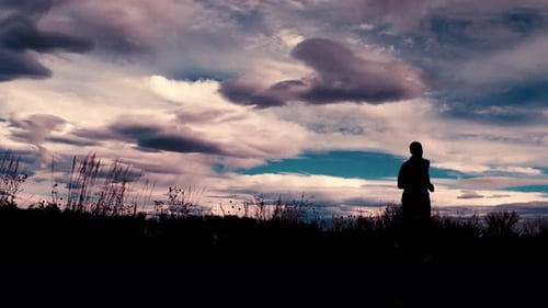Beautiful black silhouette outline of a male jogger, jogging against a dramatic sky. The jogger run