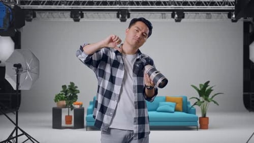 Fotógrafo chateado olhando as fotos na câmera e depois mostrando os polegares para baixo no estúdio