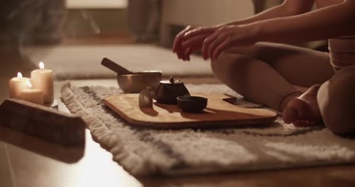 Woman Meditating and Pouring Tea by Candlelight Indoors