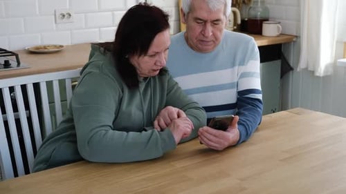 Senior Couple Viewing Smartphone Together in Kitchen