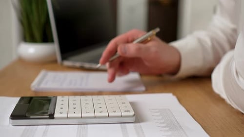 Mann arbeitet im Büro mit Taschenrechner auf dem Schreibtisch, um Berechnungen aus nächster Nähe durchzuführen