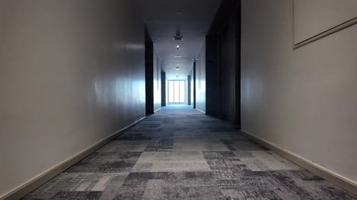 Quiet Hotel Corridor With Long Hallway Leading To Bright End, Empty And Peaceful. low angle