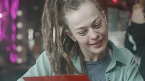 Woman Looking at Menu and Talking to her Male Friend During Lunch in Restaurant