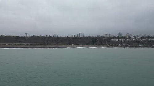 Wide aerial dolly shot of the beach in miraflores lima peru with a highway along the rocks and a vie