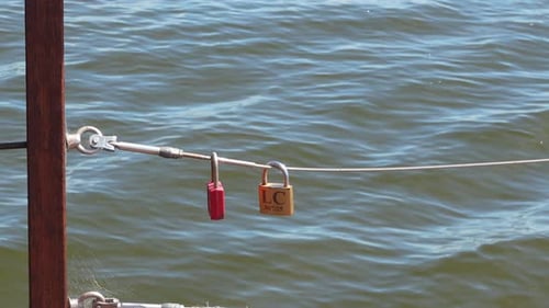 Close-up of Love Locks on Fence with Ocean Waves in Background