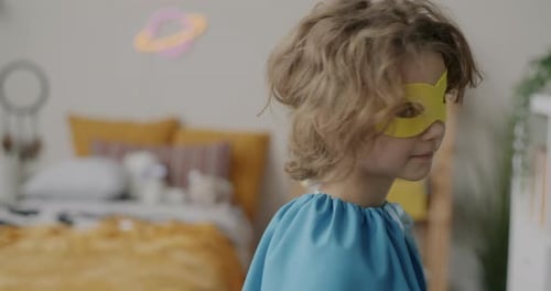 Slow Motion Portrait of Adorable Child Turning to Camera Dressedup in Superhero Mask and Cape