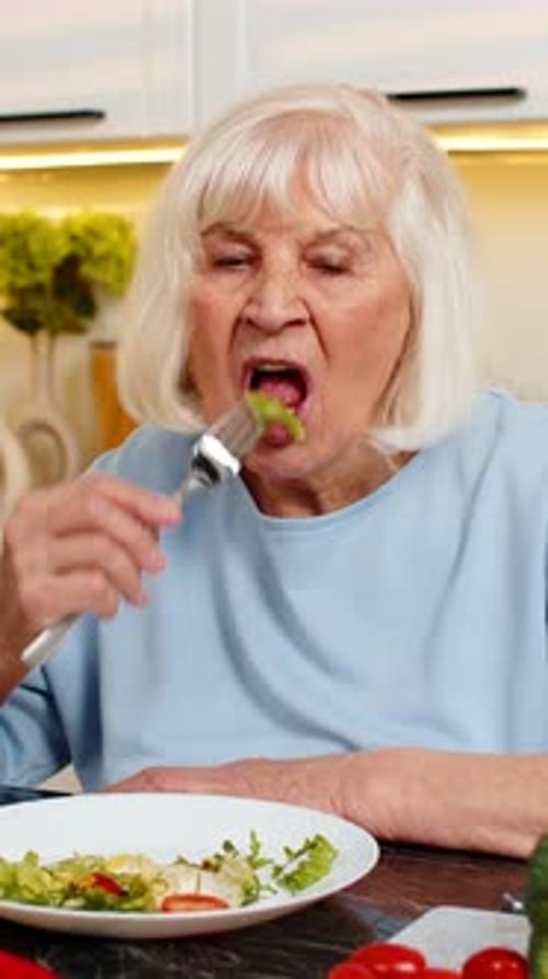 Senior Woman Enjoys Healthy Salad in Bright Kitchen