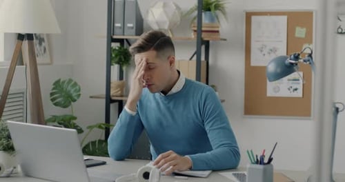 Young Adult Working at Desk Appears Frustrated