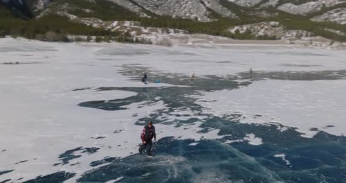 aerial view of man ice skating on frozen abraham lake in laberta, canada